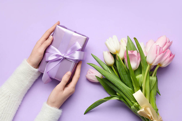 Naisten kädet lahjapaketti ja kimppu kauniita tulppaanit violetti tausta. Kansainvälinen naistenpäivä - Valokuva, kuva