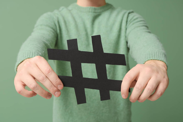 Mann mit Hashtag-Zeichen auf grünem Hintergrund, Nahaufnahme - Foto, Bild