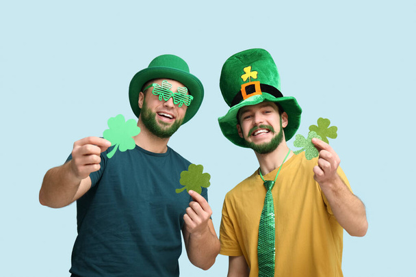 Jonge mannen met kabouter hoeden met groene baard met klaver op blauwe achtergrond. St. Patrick 's Day viering - Foto, afbeelding