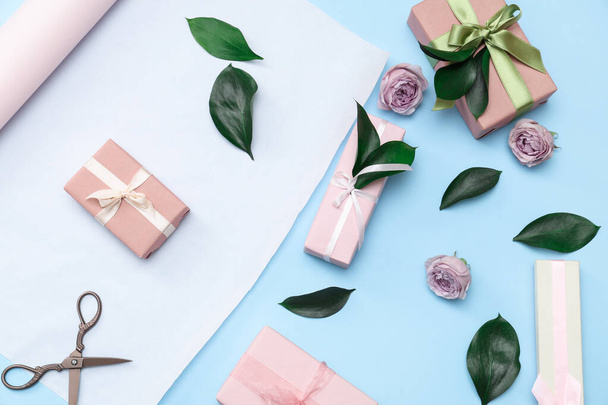Cajas de regalo, papel de regalo con hermosas rosas y hojas sobre fondo azul. Día Internacional de la Mujer - Foto, Imagen