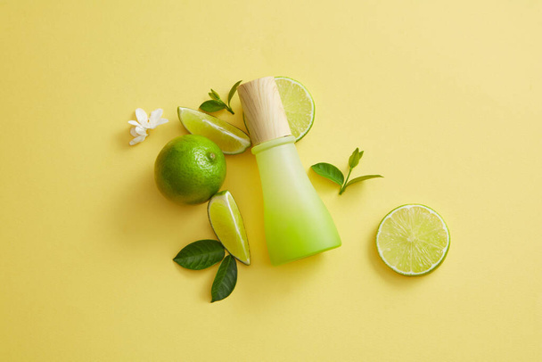 Composition of a gradient jar, leaves, flowers and Lime slices. Lime (Citrus aurantiifolia) contains a lot of vitamin C to help improve healthy and bright skin - Photo, Image