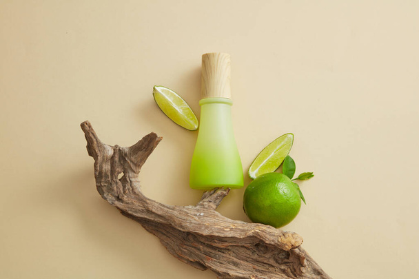 A tree branch decorated with Lime and a gradient white and green jar without label. Lime (Citrus aurantiifolia) are rich in vitamin C and minerals like potassium, calcium, and magnesium - Photo, Image