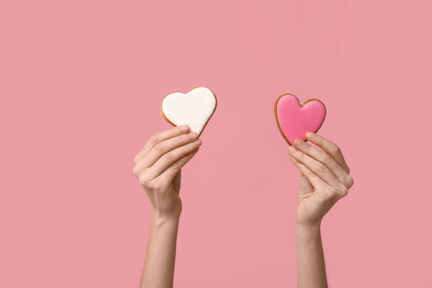 Mujer con galletas en forma de corazón sobre fondo rosa. Celebración de San Valentín - Foto, imagen