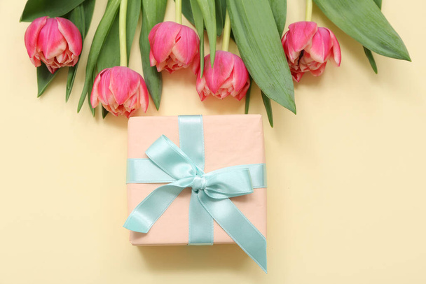 Dárková krabice a kytice krásných tulipánů na žlutém pozadí. Mezinárodní den žen - Fotografie, Obrázek