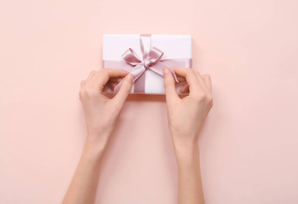 Manos femeninas con caja de regalo sobre fondo rosa. Día Internacional de la Mujer - Foto, Imagen