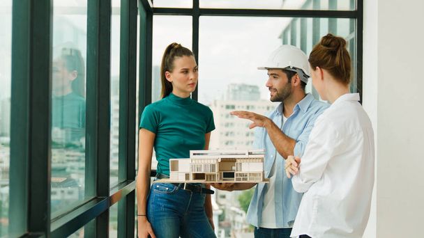 Skilled engineer holds house model and explain about house construction to skilled manager. Group of interior designer inspect architectural model. Working together, Civil engineering. Tracery - Photo, Image