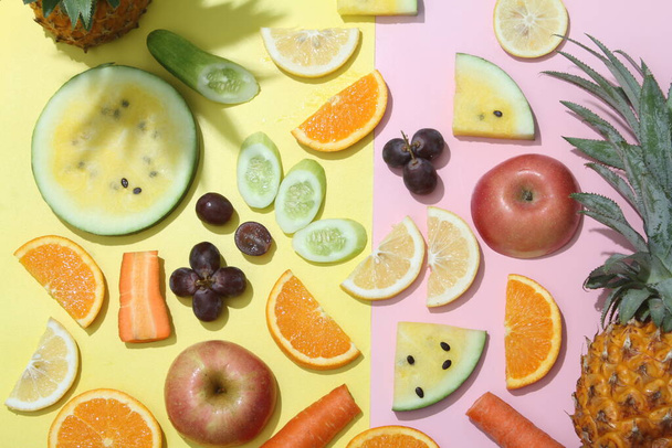 a variety of fruits and vegetables arranged on a pink and yellow background - Photo, Image