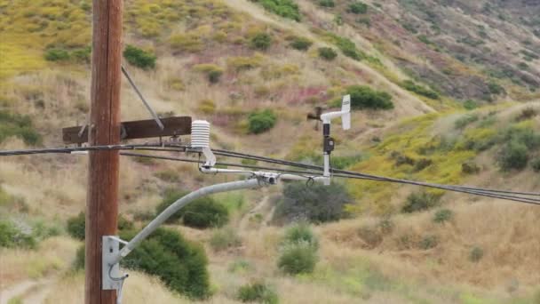 Aeromotor moderno o anemómetro que mide la velocidad y dirección del viento en las montañas de Santa Mónica, suburbios de Los Ángeles, California, Estados Unidos. Medidor de velocidad del viento girando en el pilar de potencia por el viento, imágenes de 4k - Metraje, vídeo