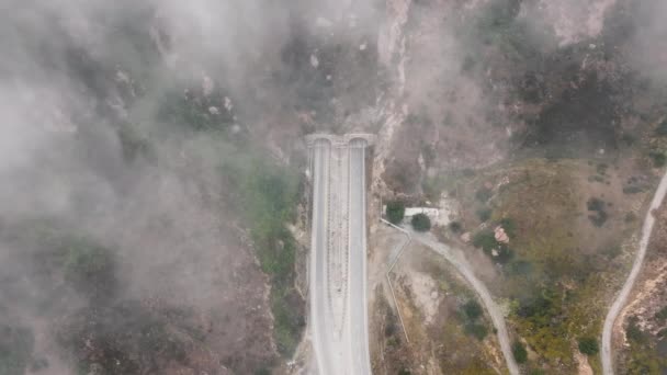 Vista dall'alto della strada Kanan che attraversa la nebbia al mattino, Malibu, periferia di Los Angeles, California, USA. Veduta aerea del tunnel nelle montagne di Santa Monica. formazioni nuvolose che coprono autostrada, filmati 4k - Filmati, video