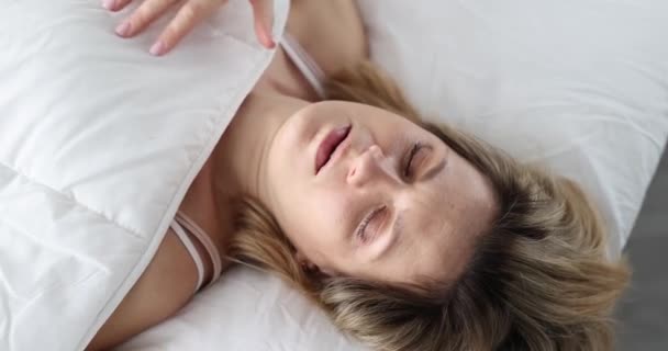 Az ébredt, sokkos fiatal nő bebújik a takaró alá. Menstruációs rendellenességek fogalma - Felvétel, videó