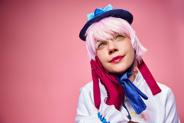 attractive fashionable woman cosplaying cute anime character and looking away on pink backdrop - Foto, afbeelding