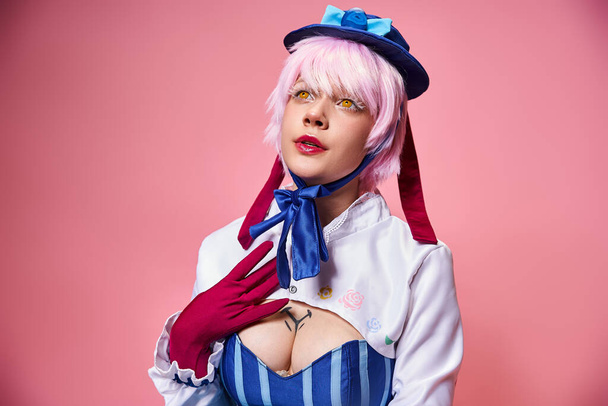 ελκυστική μοντέρνα γυναίκα cosplaying χαριτωμένο anime χαρακτήρα και κοιτάζοντας μακριά σε ροζ φόντο - Φωτογραφία, εικόνα