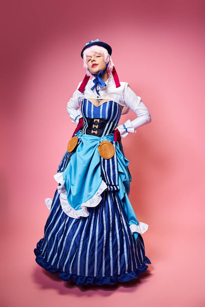 appealing female cosplayer in blue stylish hat looking at camera posing with her arms on hips - Φωτογραφία, εικόνα
