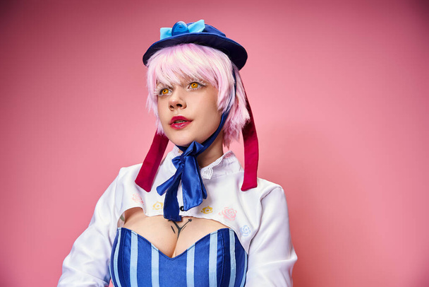 alluring fashionable woman cosplaying cute anime character and looking away on pink backdrop - Foto, Imagen