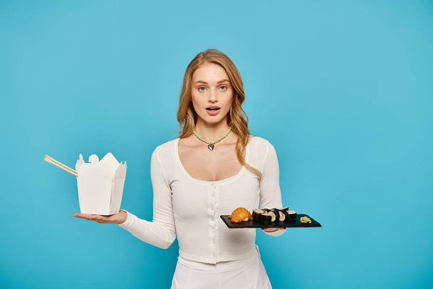 A stunning blonde woman in a white dress holds a tray of delectable Asian dishes. - Photo, Image