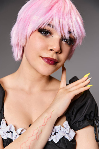 довольно заманчивый косплеер в сексуальном костюме горничной с розовыми волосами, смотрящий в камеру на сером фоне - Фото, изображение