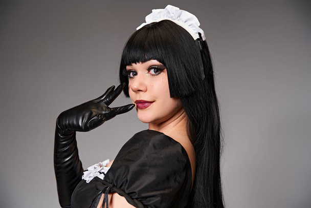 seductive sexy female cosplayer in tempting maid costume looking at camera on gray background - Foto, Imagem