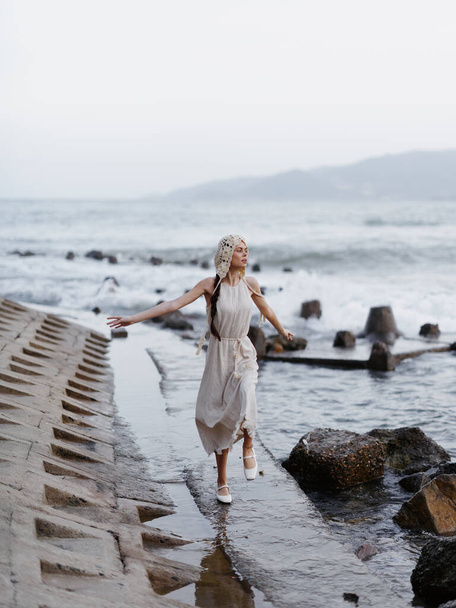 Tyyni kesäpako: Nuori, viehättävä nainen valkoisessa mekossa seisoo yksin hiekkarannalla, tuijottaen sinisen valtameren loputonta horisonttia, sisältäen kauneuden, tyylikkyyden ja vapauden.. - Valokuva, kuva