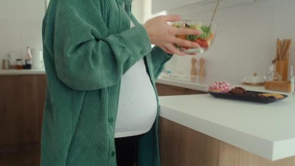Tuntematon raskaana oleva nainen, joka valitsee makeita välipaloja kuin kulhollinen salaattia - Materiaali, video