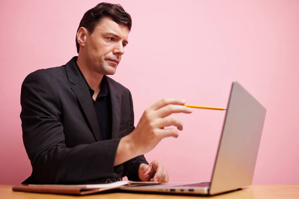 Poważny przedsiębiorca wskazujący na ekran laptopa ołówkiem podczas czytania ważnych danych lub porównywania liczb - Zdjęcie, obraz
