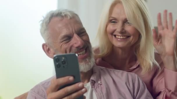 笑顔のコーカサスハッピーファミリーカップル男女祖母は,携帯アプリケーションを使用して携帯電話でビデオ通話を介して話し,スマートフォン経由のオンライン会議リモートミーティングで通信 - 映像、動画