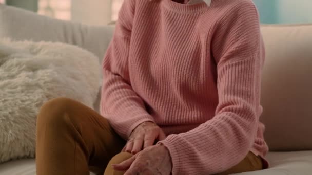 Кавказький нездоровий страждаючий артрит остеоартрит симптом старенька вдома диван літня жінка страждає від болю в коліні біль старша леді-бабуся травмування потираючи хворобливі проблеми зі здоров'ям ніг - Кадри, відео