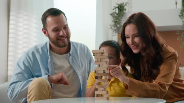 Boldog szerető játékos kaukázusi család anya apa apa szülők szeretett fiú fiú gyerek játék intellektuális logikai társasjáték együtt hangulatos nappali játék torony puzzle élvezze játékok otthon - Felvétel, videó
