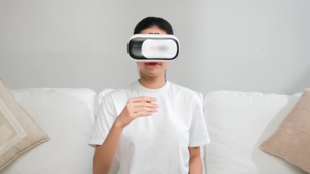 Νεαρή γυναίκα που χρησιμοποιεί εικονική πραγματικότητα VR goggle στο σπίτι για vivancy online εμπειρία αγορών. Η καινοτομία εικονικής πραγματικότητας VR βελτιστοποιημένη για τον γυναικείο τρόπο ζωής ψηφιακής ψυχαγωγίας. - Πλάνα, βίντεο