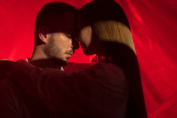 2人の恋人はネオンライトの背景に抱きしめます. 屋内でボーイフレンドに触れる女性. 情熱的な芸術愛の概念. 関係におけるフォープレイ 4k 映像 - 写真・画像