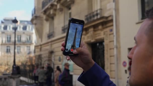 Parijs, Frankrijk: 25 oktober 2023: Een schietpartij met zijn smartphone Eiffeltoren in Parijs. Man toerist met telefoon fotograferen beste uitzicht op Eiffelstructuur gebouw. Hoge kwaliteit 4k - Video