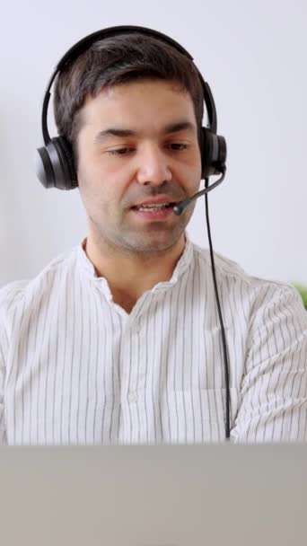 Diffuseur hispanique parlant sur ordinateur portable. Un jeune homme positif portant un casque. Concept de service d'assistance téléphonique - Séquence, vidéo