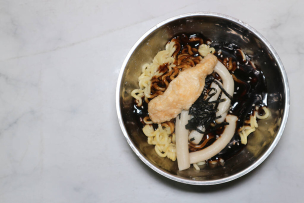Vista superior de la comida coreana Rabboki (pastel de arroz frito y fideos Ramen) espolvoreado con nori (algas marinas) en un tazón de metal con fondo blanco de Corea del Sur - Foto, Imagen