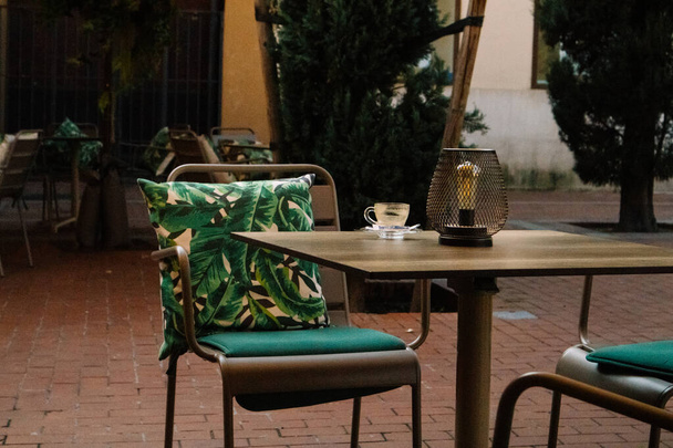 Vista de um aconchegante terraço com mobiliário de jardim - mesas e cadeiras com almofadas com folhas de palmeira tropicais verdes. Hotel restaurante quintal. - Foto, Imagem