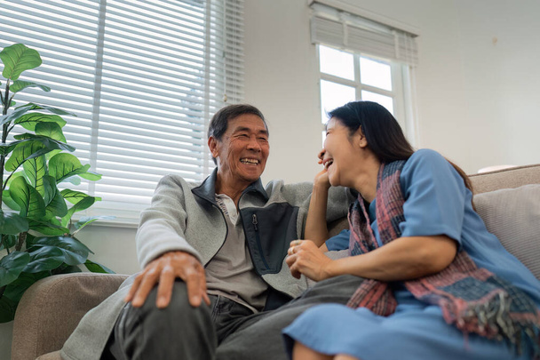 Ältere Paare sitzen am Wochentag entspannt und glücklich auf dem heimischen Sofa und unterhalten sich.. - Foto, Bild