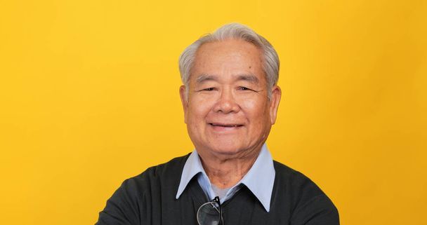 Крупним планом портрет літнього чоловіка, який посміхається і дивиться на камеру. Ізольовані на жовтому тлі в студії. - Фото, зображення
