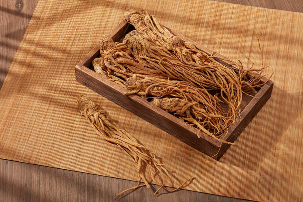 Angelica gyökeret tett egy fa tálcára és bambusz vakra. Az emberek használják Angelica gyökér (Angelica sinensis) szépít, javítja az egészséget, és kezelésére keringési és bőrbetegségek - Fotó, kép