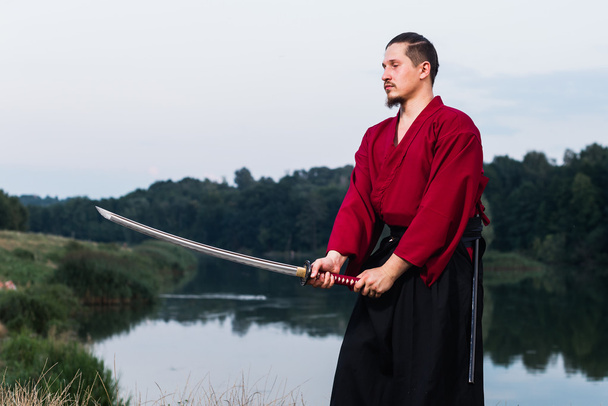 Мужчина в японской форме самурая с мечом катаны
 - Фото, изображение