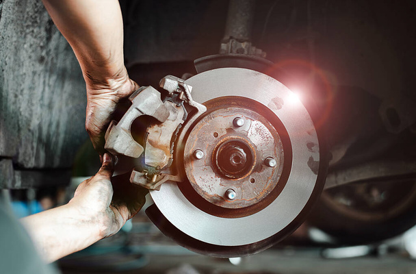 Bir arabanın disk fren sistemi üzerinde çalışan bir tamircinin ellerinin yakın plan çekimi, bakım ve onarım - Fotoğraf, Görsel