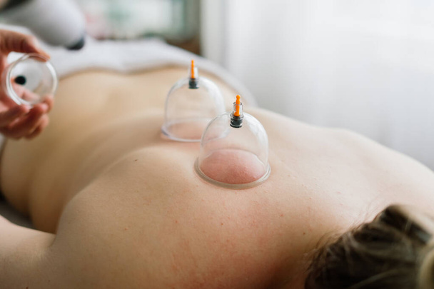 A woman does a hip massage with vacuum jar for an anti-cellulite massage. - Photo, Image