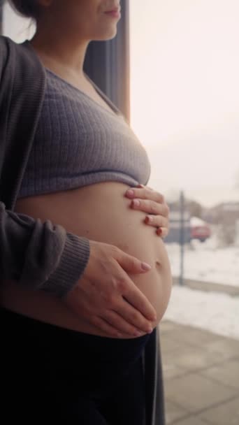 Vertikální video nerozpoznatelné bělošky těhotné ženy dotýkající se jejího břicha - Záběry, video