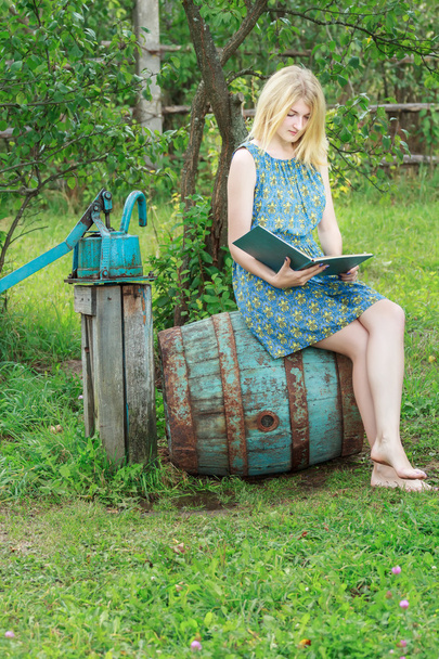 Студентська дівчина босоніж у блакитній шовковій жіночій сукні читає книгу
 - Фото, зображення