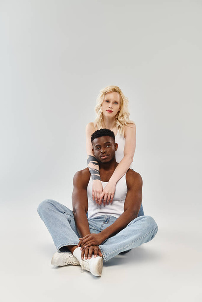 Ein Mann sitzt auf dem Boden und stützt eine Frau auf seinem Rücken, die im Studio Vertrauen, Gleichgewicht und Verbundenheit demonstriert. - Foto, Bild