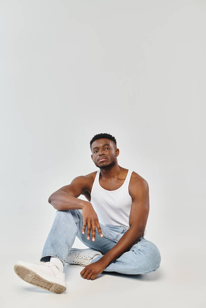 Genç bir Afro-Amerikalı adam yerde bağdaş kurarak oturuyor, dinginlik ve içgözlem hissi yayıyor.. - Fotoğraf, Görsel