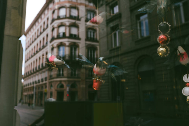 Egy kávézóban a játékmadarak kávét tartanak, míg az üveg a városképet tükrözi, érdekes látványt nyújtva. - Fotó, kép