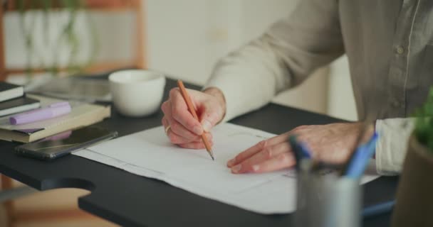 Sección central de diseño de dibujo de hombre de negocios en papel mientras está sentado en el escritorio en la oficina - Metraje, vídeo