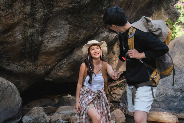 Ein asiatisches Paar verbrachte seinen Urlaub beim Wandern entlang des Naturlehrpfades, beim Besuch des Wasserfalls und beim gemeinsamen Genießen der Waldaussichten... - Foto, Bild