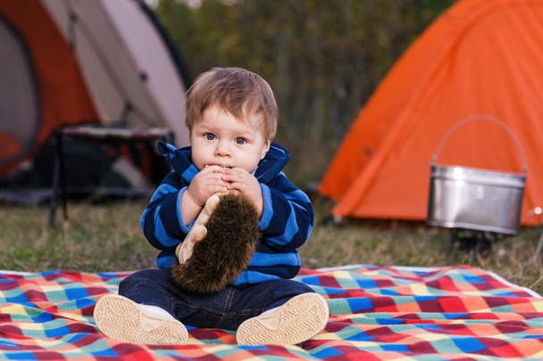 malý chlapec si hraje s medvídkem v trávě - Fotografie, Obrázek