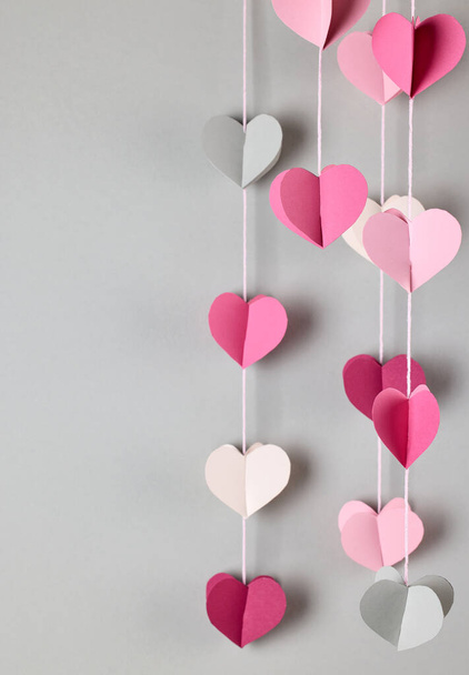 kleurrijke decoratieve papieren harten opknoping op grijze achtergrond, selectieve focus - Foto, afbeelding