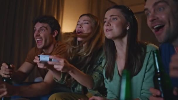 幸せな友人とホームソファーでビデオゲームをプレイする感情的な女の子が近づいています. 笑顔のマットは,週末の夕方に友好的な競争を楽しんでいます. 夜のハングアウトで勝利を喜ぶコンソールを持つ楽しい女性. - 映像、動画