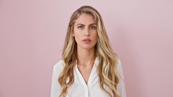 Skeptisch aussehende junge blonde Frau, die nicht überzeugt ist, sarkastisch verblüfftes Gesicht mit offenem Mund, ausdrucksstarke Augen vor rosa isoliertem Hintergrund - Filmmaterial, Video